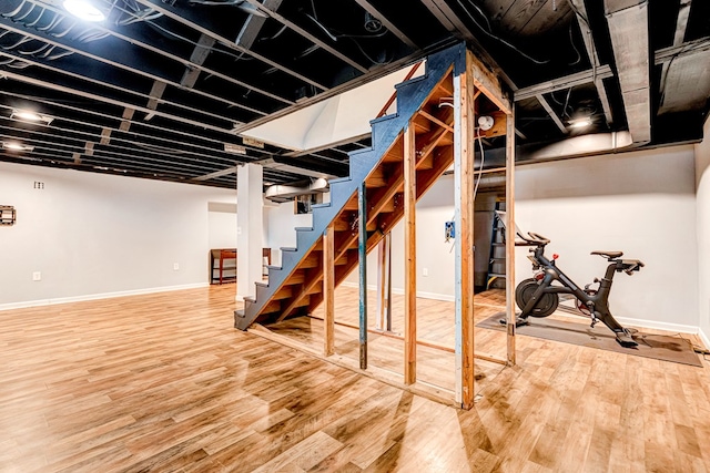 finished below grade area featuring baseboards, stairway, and wood finished floors