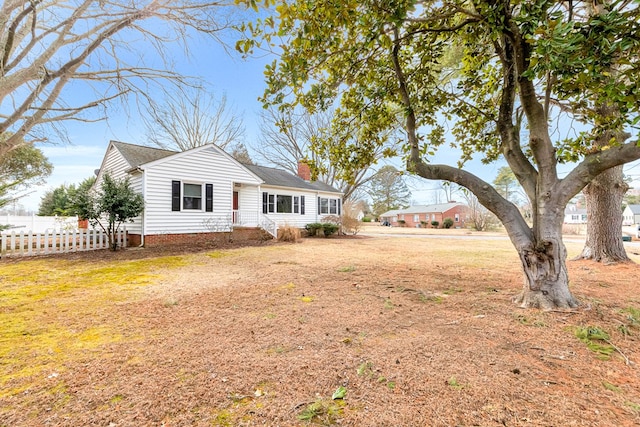 view of front of home featuring a chimney, a front yard, and fence