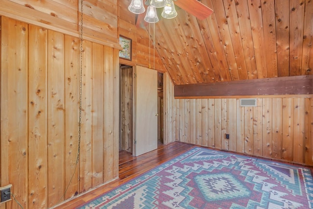 additional living space featuring vaulted ceiling with beams, wooden walls, and wood-type flooring