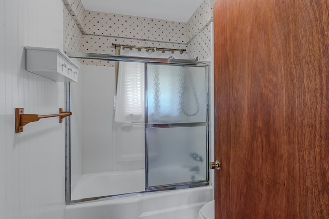 bathroom with toilet and combined bath / shower with glass door