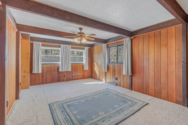 spare room featuring carpet, ceiling fan, and wood walls