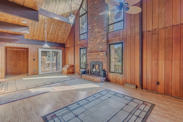 interior space featuring beam ceiling, wooden walls, high vaulted ceiling, and light wood-type flooring