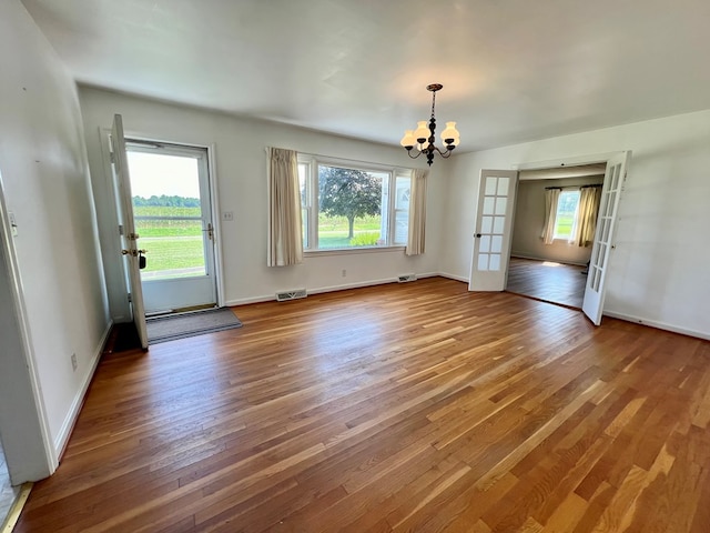 interior space with hardwood / wood-style flooring, a chandelier, and french doors