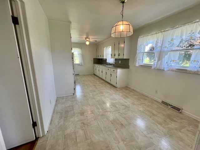 kitchen with ceiling fan, sink, white cabinetry, and hanging light fixtures