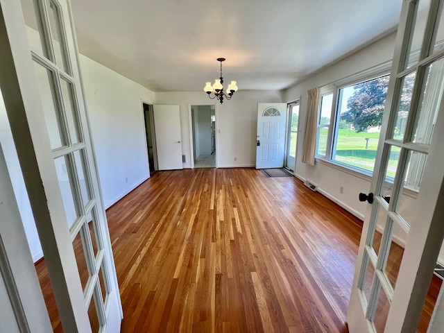 spare room featuring french doors, a chandelier, and hardwood / wood-style flooring