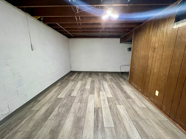 basement featuring wooden walls and light hardwood / wood-style flooring