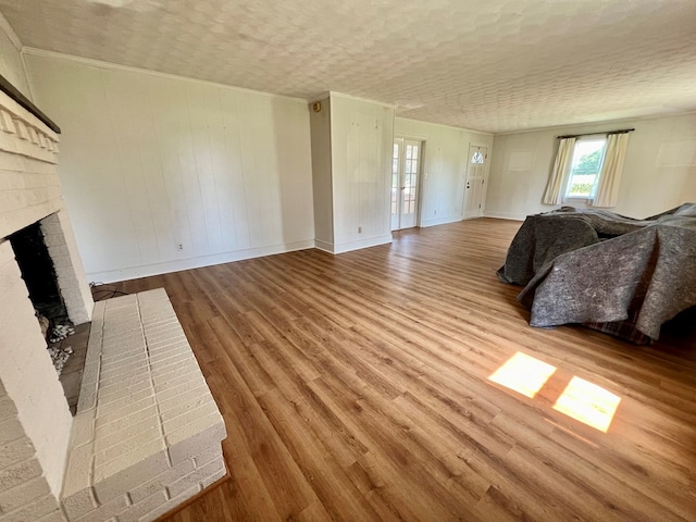 living room featuring a textured ceiling, hardwood / wood-style flooring, and a brick fireplace