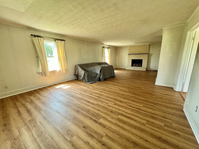 unfurnished bedroom with a textured ceiling, light hardwood / wood-style floors, and a fireplace