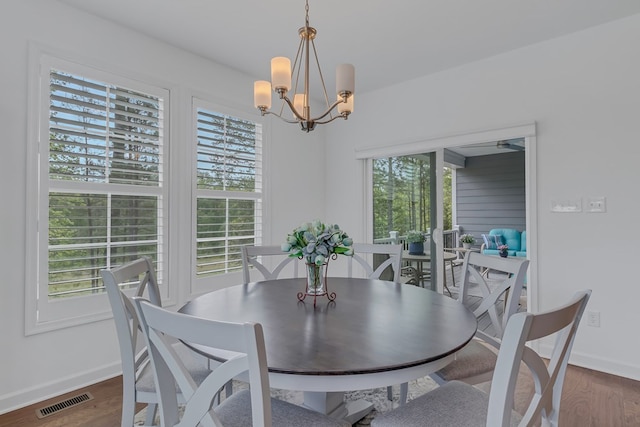 dining area with dark hardwood / wood-style floors and a notable chandelier