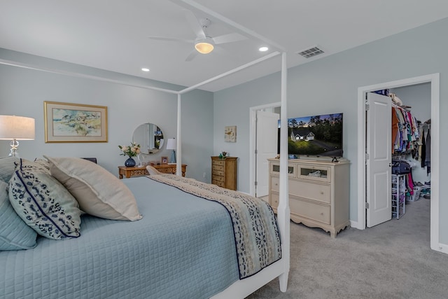 carpeted bedroom with a walk in closet, ceiling fan, and a closet