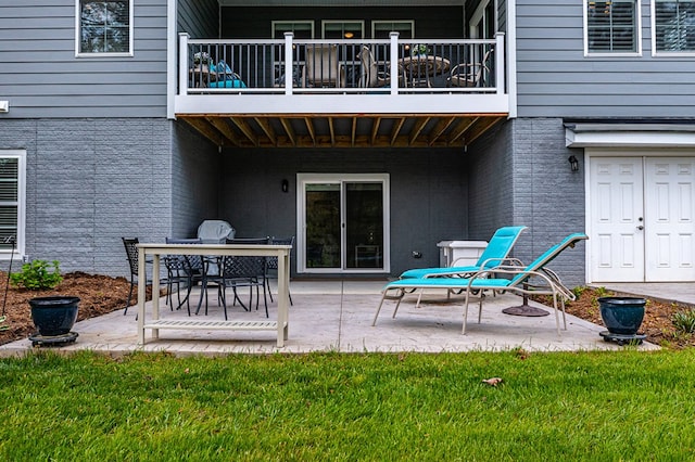 back of house featuring a balcony, a patio area, and a lawn