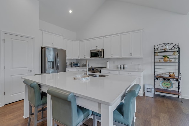 kitchen with appliances with stainless steel finishes, a kitchen breakfast bar, a kitchen island with sink, and white cabinets