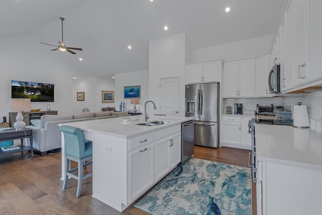 kitchen featuring white cabinetry, stainless steel appliances, dark wood-type flooring, and a center island with sink