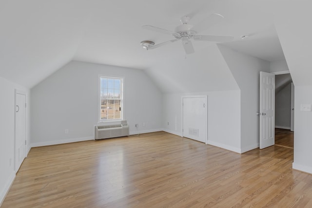 additional living space featuring light hardwood / wood-style floors, ceiling fan, a wall mounted AC, and lofted ceiling