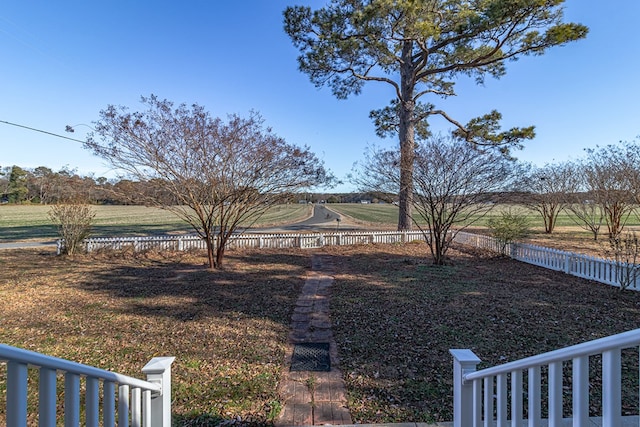 view of yard with fence and a rural view