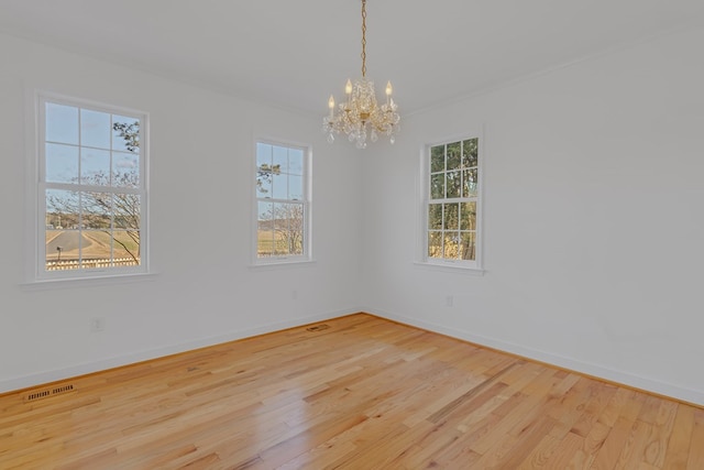 unfurnished room featuring visible vents, a notable chandelier, light wood-style flooring, and baseboards