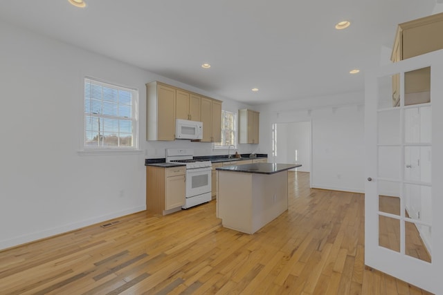 kitchen with white appliances, baseboards, a center island, light wood finished floors, and dark countertops