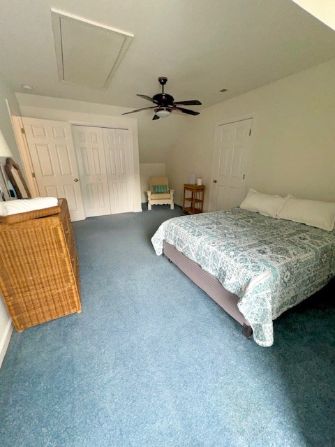 carpeted bedroom with attic access, a ceiling fan, and a closet