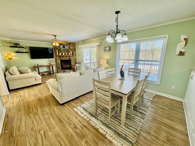 dining space featuring ornamental molding, light wood finished floors, a fireplace, and baseboards