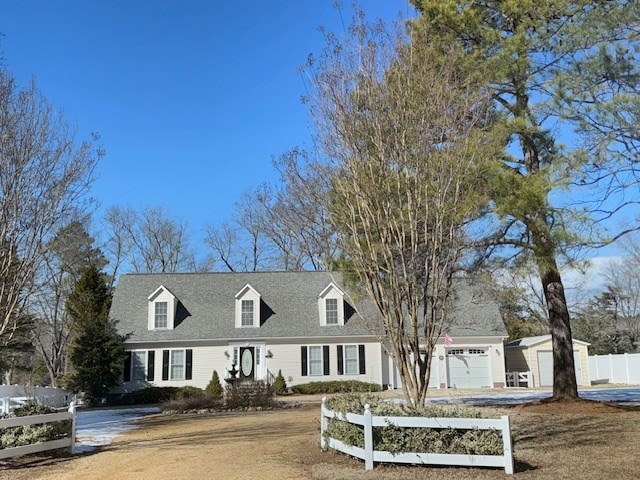 cape cod house featuring fence, driveway, and an attached garage