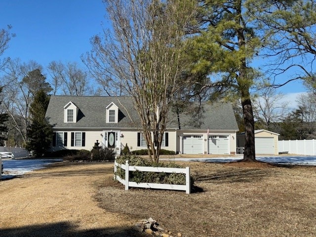 new england style home with driveway, an attached garage, and fence