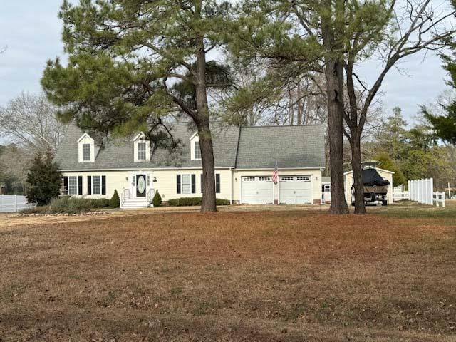 new england style home featuring an attached garage and fence