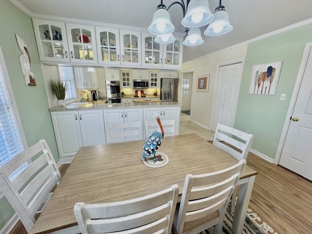 dining space featuring ornamental molding, baseboards, light wood finished floors, and an inviting chandelier