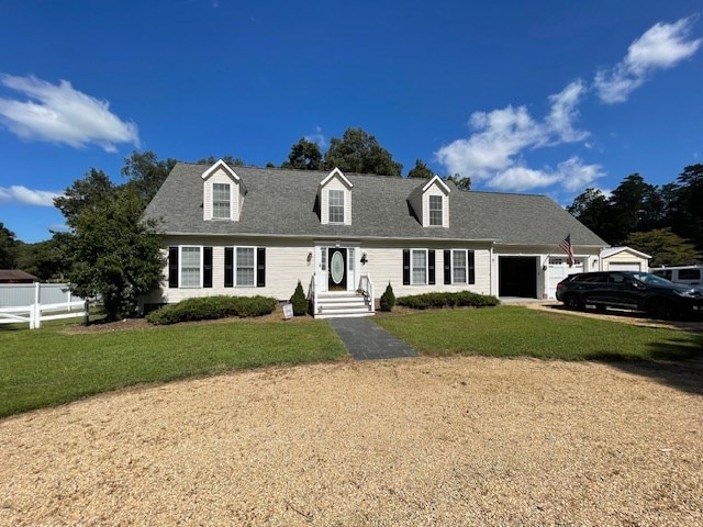 cape cod-style house featuring a garage, a front lawn, and fence