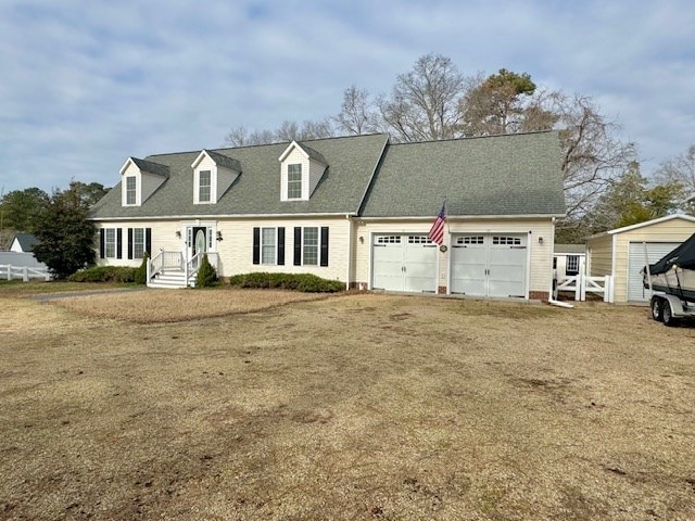 cape cod house with roof with shingles and dirt driveway