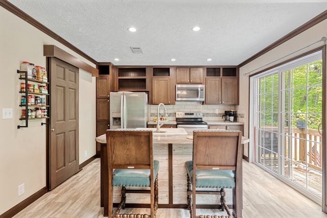 kitchen featuring open shelves, a sink, light countertops, ornamental molding, and stainless steel appliances