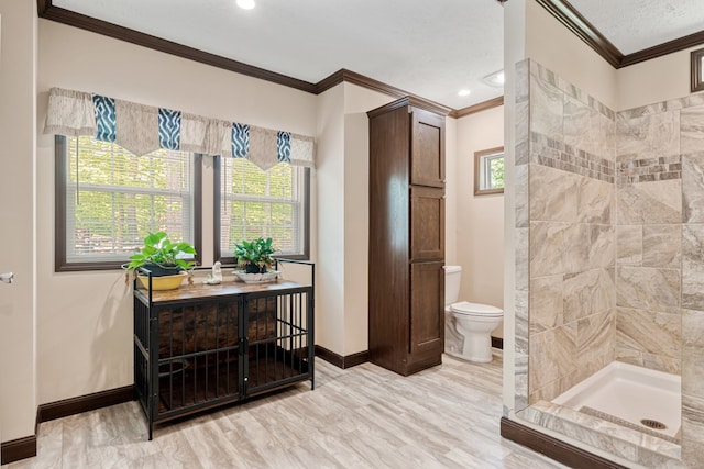 full bathroom featuring crown molding, toilet, baseboards, and a stall shower