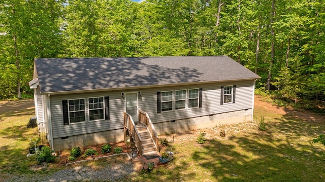 view of front of property featuring roof with shingles, crawl space, and a forest view