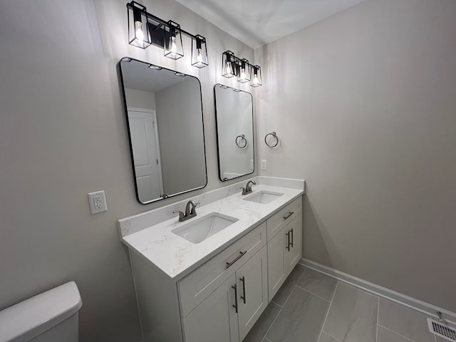 605 Shorewood Dr, Colonial Beach, VA 22443 - bathroom featuring double vanity, toilet, marble finish floors, and baseboards