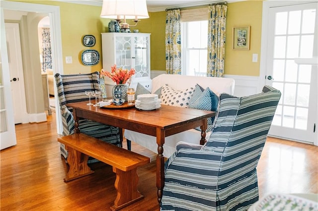 dining area featuring light wood-style floors, ornamental molding, and a wainscoted wall