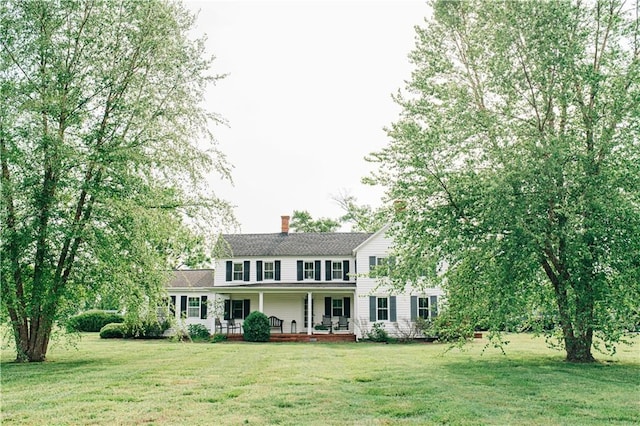 colonial-style house with a chimney, covered porch, and a front yard