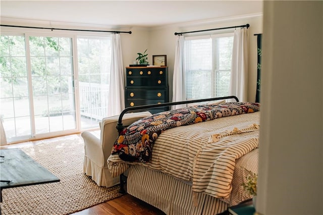 bedroom featuring multiple windows, access to exterior, crown molding, and wood finished floors