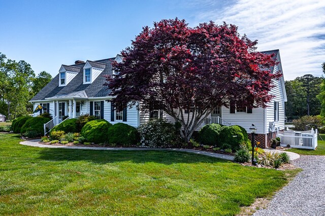 cape cod-style house with a chimney and a front yard