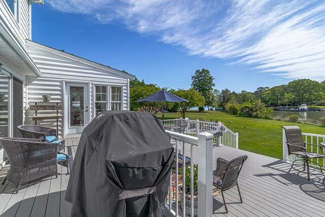 wooden terrace featuring a yard, a water view, and a grill