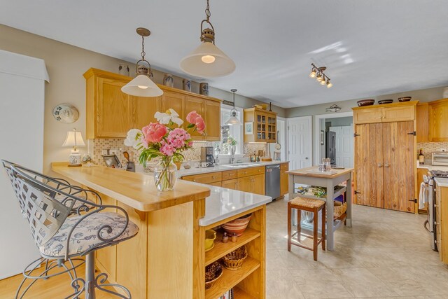 kitchen with a peninsula, light countertops, a sink, backsplash, and stainless steel appliances