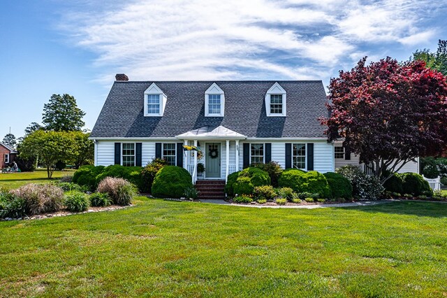 cape cod house with a chimney and a front yard