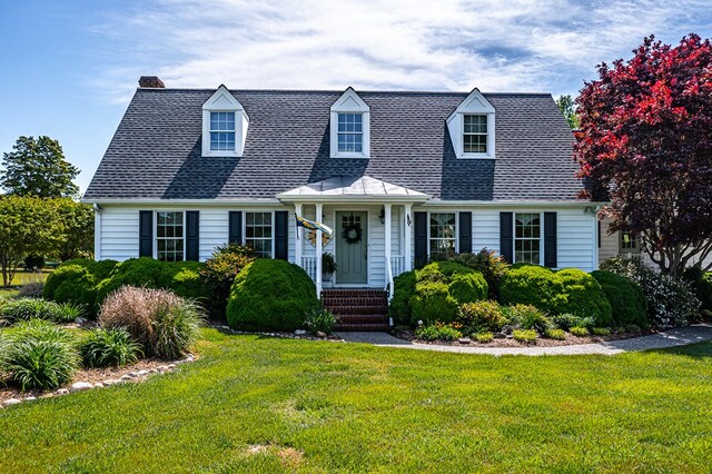 cape cod house featuring roof with shingles and a front yard