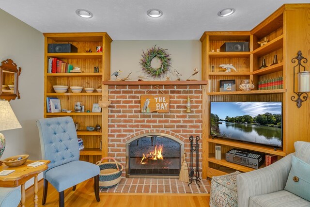 living area featuring a brick fireplace and wood finished floors