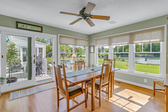 sunroom / solarium featuring wood-type flooring, baseboards, a wooden deck, and a wealth of natural light