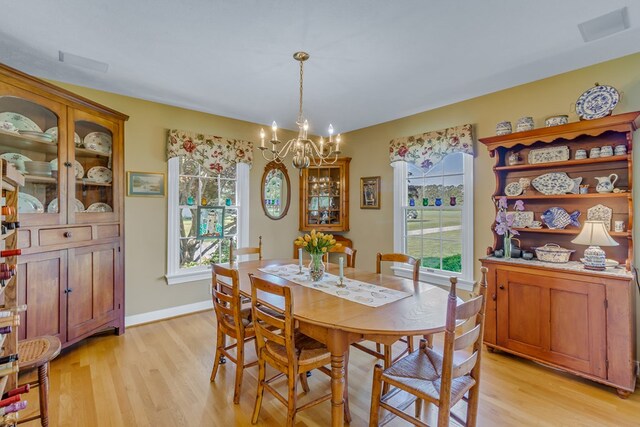 dining space with an inviting chandelier, baseboards, and light wood-type flooring