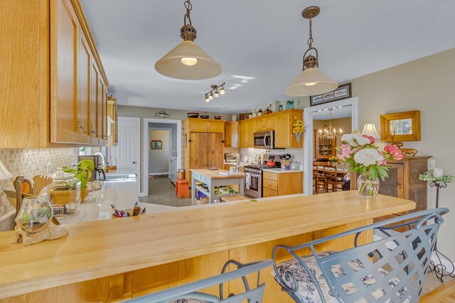 kitchen featuring appliances with stainless steel finishes, tasteful backsplash, a sink, light countertops, and a chandelier