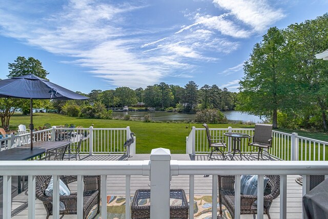 wooden deck with outdoor dining area, a water view, and a lawn