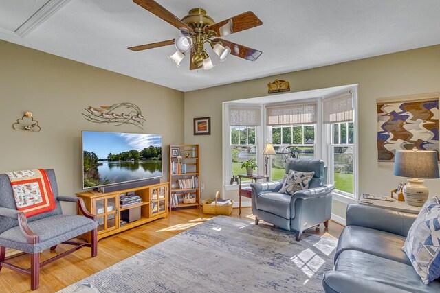 living area with a ceiling fan, baseboards, and wood finished floors