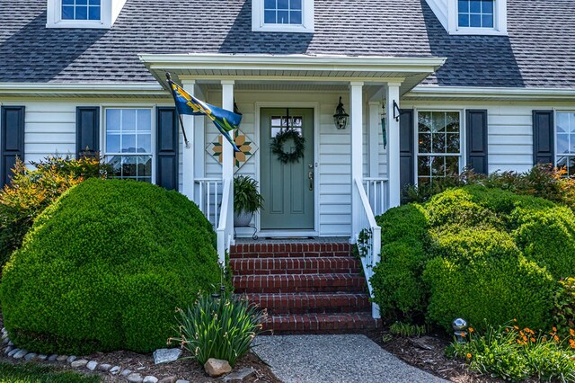 view of exterior entry featuring a shingled roof