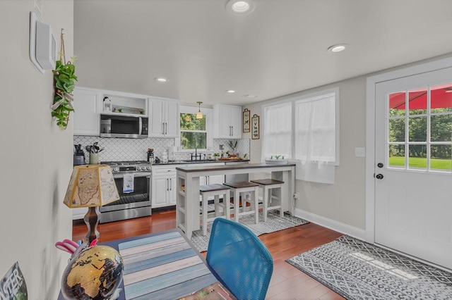 kitchen featuring appliances with stainless steel finishes, a wealth of natural light, sink, light hardwood / wood-style flooring, and white cabinets