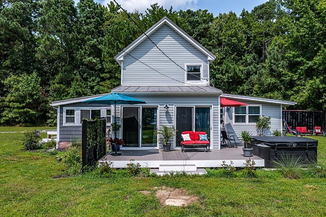 back of house featuring a hot tub, a lawn, and a wooden deck